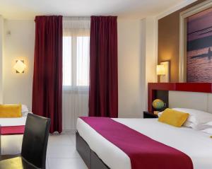 a hotel room with two beds and red curtains at Kairos Garda Hotel in Castelnuovo del Garda
