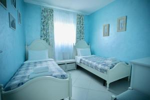 a blue room with two beds and a window at Dimora di Luce in Pezze di Greco