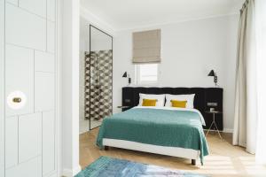 a bedroom with a bed with a green blanket and yellow pillows at No.4 Residence in Warsaw