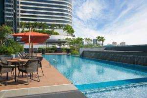 a pool with a table and chairs and an umbrella at Holiday Inn Singapore Little India, an IHG Hotel in Singapore
