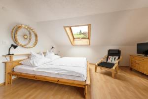 1 dormitorio con 1 cama con espejo y silla en WÄLDERHAUS Apartments, en Schwarzenberg im Bregenzerwald