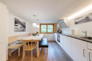 a kitchen with white cabinets and a wooden table at WÄLDERHAUS Apartments in Schwarzenberg im Bregenzerwald