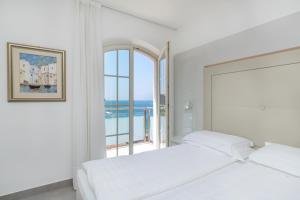 a white bedroom with two beds and a window at Hotel Vega in Malcesine