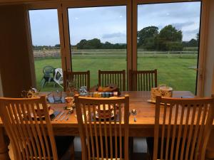 a dining room table with chairs and a large window at Folly Fields Farm B&B in Sherborne