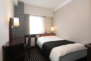 a hotel room with a bed and a window at APA Hotel Wakayama in Wakayama