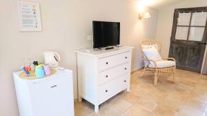 a white dresser with a television on top of it at La Ferme Les Eybrachas in Réauville