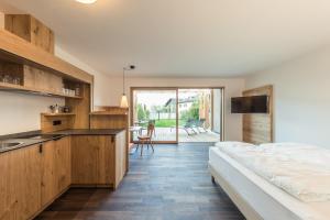 ein Schlafzimmer mit einem Bett und eine Küche mit einem Waschbecken in der Unterkunft Weingut Moser Apartments in Kaltern