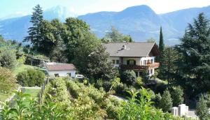 een huis op een heuvel met bergen op de achtergrond bij Oberjaistenhof in Lana