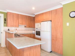 a kitchen with wooden cabinets and a white refrigerator at 1 54 Parkes Street in Tuncurry
