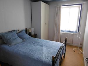 1 dormitorio con 1 cama con edredón azul y ventana en LA MUSARDIERE en Auzouer-en-Touraine