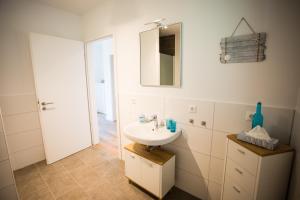 a bathroom with a sink and a mirror at Strandchalet Elmo II in Wremen +23 photos
