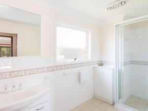 a white bathroom with a sink and a mirror at 11 Bay Street - waterfront holiday in Tuncurry