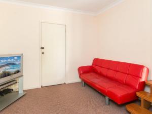a red couch in a living room with a tv at 11 Peel Street in Tuncurry