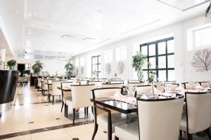 a dining room with tables and chairs and windows at Hotel Epoque & Apartments in Pietarsaari