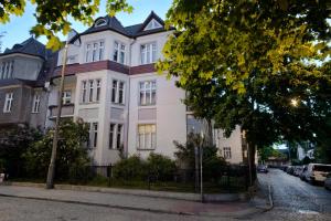 una gran casa blanca con techo negro en Apartament Molo en Sopot