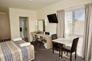 a hotel room with a bedroom with a desk and a bed at Pioneer Motel Goondiwindi in Goondiwindi