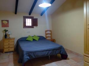 ムルシアにあるFinca El Carrascalのベッドルーム1室(青いシーツと緑の枕が備わるベッド1台付)
