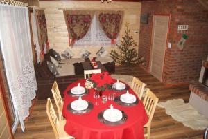 Una habitación con una mesa roja con un árbol de Navidad. en Domek Całoroczny OSTOJA en Istebna