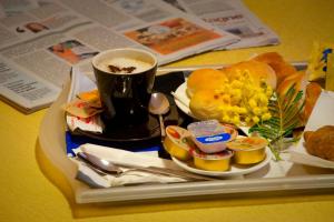 a tray with a cup of coffee and a plate of food at Hotel Boccascena in Genoa