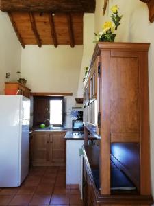 cocina con armarios de madera y nevera blanca en Casa Rural La Pontezuela Abajo, en Navarredonda de Gredos