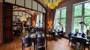 a dining room with tables and chairs and windows at Conferentiecentrum Hotel Bovendonk in Hoeven