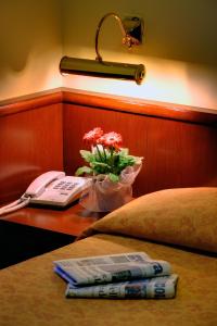 a bed with a phone and flowers on a table at Hotel Boccascena in Genoa