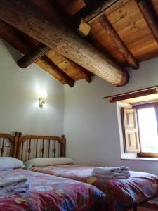 ナバレドンダ・デ・グレドスにあるCasa Rural La Pontezuela Arribaの木製天井と窓が備わるベッドルーム1室(ベッド2台付)
