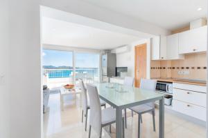 uma cozinha com uma mesa de vidro e cadeiras brancas em Luisamar Sea View em Manacor