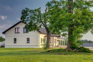 Una casa blanca con un árbol delante. en Folwark Żabowo, en Glinojeck