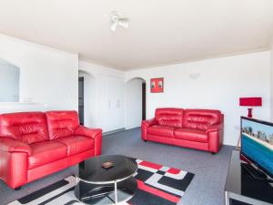 a living room with two red couches and a tv at Albert Court 8 in Forster