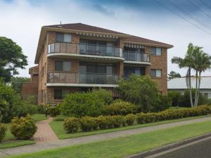 a brick apartment building with a balcony and trees at Braemar 9 in Forster