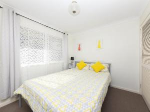 um quarto com uma cama com almofadas amarelas e uma janela em Capeview em Forster