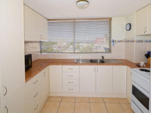 a kitchen with white cabinets and a sink and a window at Ebbtide 26 in Forster