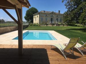 - une piscine avec 2 chaises et une maison dans l'établissement Belle maison bourgeoise de charme dans un domaine viticole, à Libourne