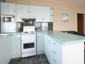 a kitchen with white cabinets and a white stove top oven at Debra Court 6 in Forster