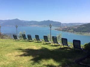 a row of chairs sitting on the grass near a body of water at B&B La Forcella in Sarnico