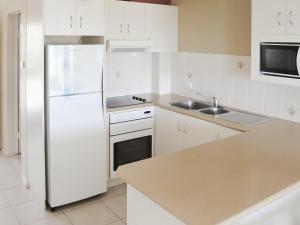 a white kitchen with a refrigerator and a sink at Fairholme 5 in Tuncurry