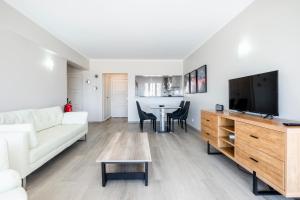 een woonkamer met een witte bank en een flatscreen-tv bij Vista Mar e Terra in Albufeira