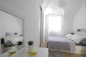 een witte slaapkamer met een bed en een spiegel bij Stone gate in Zagreb