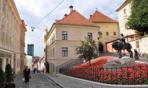 una estatua de un hombre sobre un caballo en una cama de flores en Stone gate, en Zagreb