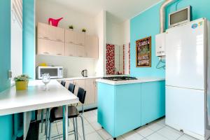 a kitchen with blue walls and a white refrigerator at Apartments na Efimova 1 in Saint Petersburg