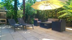 a patio with chairs and a yellow umbrella at Le patio d'olivier in Lalinde