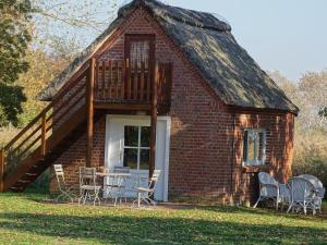 uma casa com telhado de palha, mesa e cadeiras em Der Ferienhof am Meer em Fehmarn