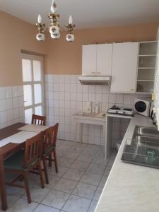a kitchen with white cabinets and a table and chairs at Tekergő Vendégház in Balatonfüred