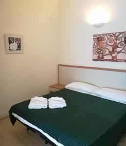 a bedroom with a green bed with towels on it at Serendipity in Rome