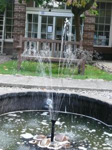 a fountain in a pond in front of a bench at Luther King House in Manchester