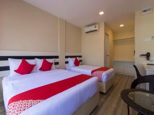 um quarto de hotel com duas camas e uma mesa em Super OYO 1145 Lea Guest House & Cafe em Lukut