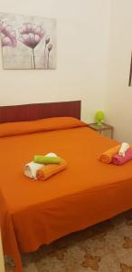 a bed with orange sheets and towels on it at Case Nausica in Marina di Ragusa