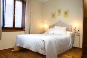 1 dormitorio con 1 cama blanca y 2 lámparas en Hostal El Palacio, en Valencia de Don Juan