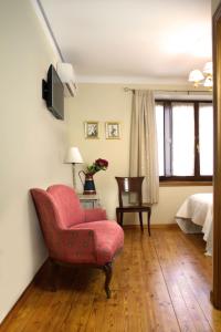 a living room with a red chair and a bed at Hostal El Palacio in Valencia de Don Juan